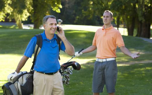Golfer using a cellphone while on a golf course.